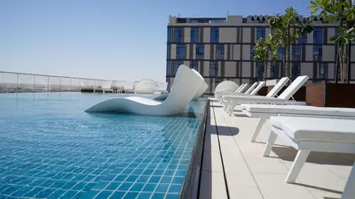 a pool with white chairs and a slide on a building at Staybridge Suites Dubai Al-Maktoum Airport by IHG in Dubai