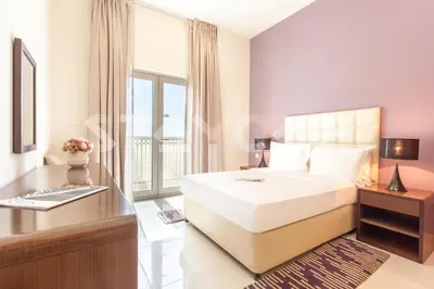 a bedroom with a bed and a desk and a window at Staycae Holiday Homes - Suburbia in Dubai