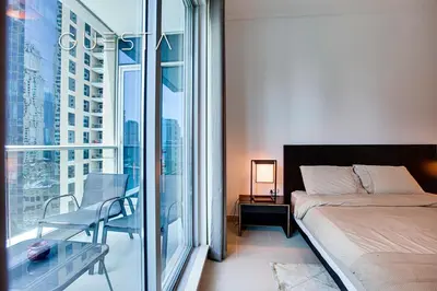 a bedroom with a bed and a glass window at Marina Promenade - Paloma Tower, Dubai Marina in Dubai