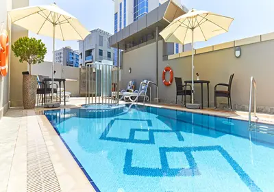 a swimming pool with umbrellas on a building at Rose Plaza Hotel Al Barsha in Dubai