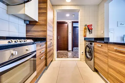 a kitchen with wooden cabinets and a washer and dryer at 5 star Sparkle Tower by Swarovski, Dubai Marina in Dubai