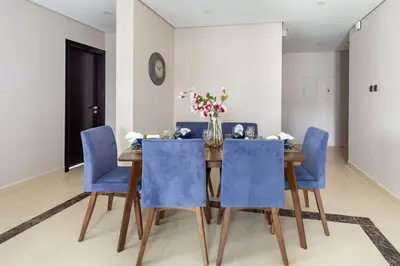 a dining room table with blue chairs and a vase of flowers at Frank Porter - Mon Reve in Dubai