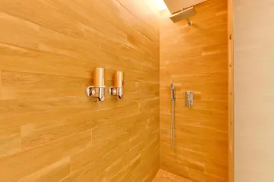 a bathroom with a shower with a wooden wall at Contemporary and Spacious 2 BR in Bluewaters Island in Dubai