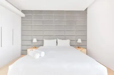 a white bedroom with a white bed and two lamps at Posh 2 BR Oceanfront Apt in the Heart of Bluewaters Island in Dubai
