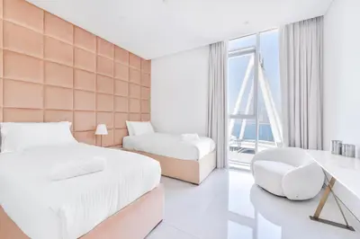a bedroom with two beds and a chair at Spectacular 3 BR condo with maids room facing the Dubai Eye in Dubai