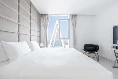 a bedroom with a large white bed and a chair at Spectacular 3 BR condo with maids room facing the Dubai Eye in Dubai