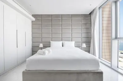 a white bedroom with a large bed and a window at Spectacular 3 BR condo with maids room facing the Dubai Eye in Dubai
