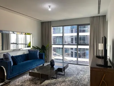 a living room with a blue couch and large windows at BELLEVUE Downtown Dubai in Dubai