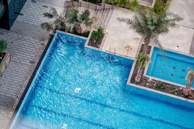 an overhead view of a swimming pool with palm trees at HiGuests - Unique Studio With Stunning Panoramic Marina Views in Dubai