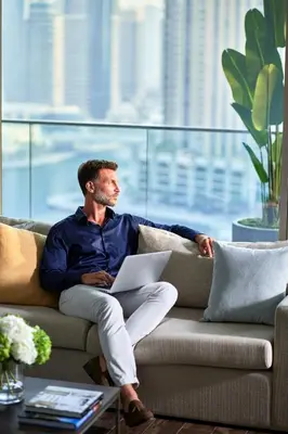 a man sitting on a couch with a laptop at Jumeirah Living Marina Gate in Dubai