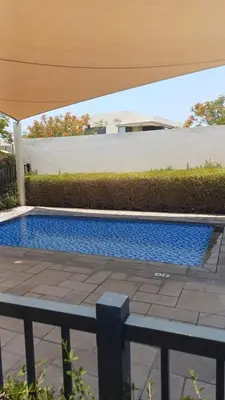 a swimming pool sitting under a patio umbrella at 5 bedroom Villa - Dubai Hills in Dubai