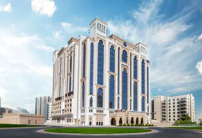 a large white building with blue windows at Al Jaddaf Rotana Dubai in Dubai