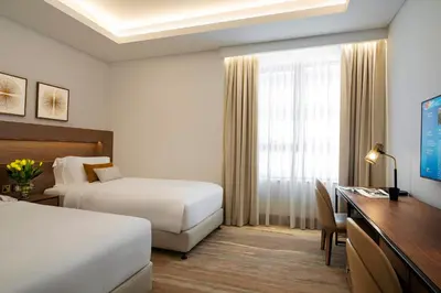 a hotel room with two beds and a desk at Al Jaddaf Rotana Dubai in Dubai