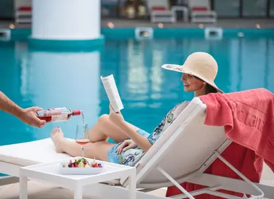 a woman sitting in a chair next to a pool at Al Jaddaf Rotana Dubai in Dubai