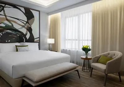 a bedroom with a bed and a chair and a window at Al Jaddaf Rotana Dubai in Dubai