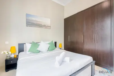 a bedroom with a large bed with a wooden cabinet at Overlooking Marina Canal 1BR Close to Mall, Promenade & Beach, Bay Central 1, Dubai Marina by Deluxe Holiday Homes in Dubai