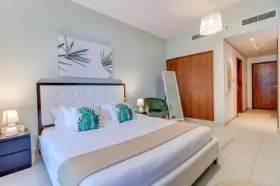 a bedroom with a large white bed with blue pillows at Durrani Homes - Luxurious Studio near Dubai Mall with pool view in Dubai