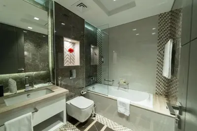 a bathroom with a tub and a toilet and a sink at SUHA Mina Rashid Hotel Apartments in Dubai