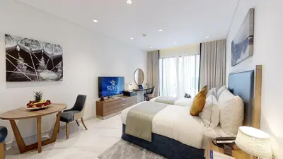a hotel room with a bed and a desk and a table at SUHA Mina Rashid Hotel Apartments in Dubai