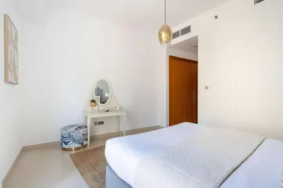 a white bedroom with a bed and a mirror at Frank Porter - Trident Grand in Dubai