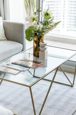 a glass coffee table with a vase of flowers on it at Frank Porter - Studio One in Dubai