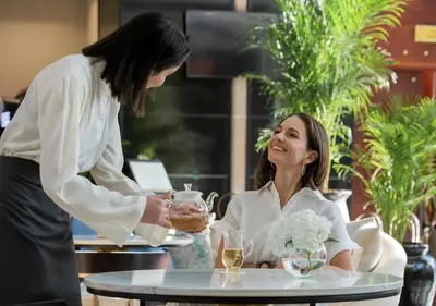 a woman sitting at a table talking to a waitress at Dusit Thani Dubai in Dubai