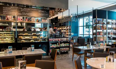 a restaurant with tables and chairs and shelves of food at Dusit Thani Dubai in Dubai
