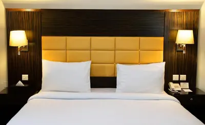 a large bed with white pillows and a yellow headboard at Fortune Karama Hotel in Dubai