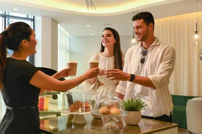 a group of people standing around a table with drinks at Arabian Park Dubai, an Edge by Rotana Hotel in Dubai