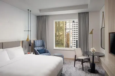 a hotel room with a bed and a chair and a window at Towers Rotana - Dubai in Dubai