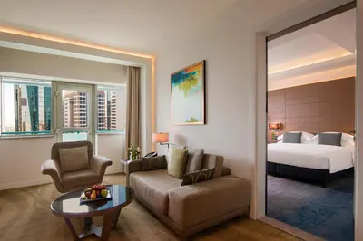 a hotel room with a bed and a couch and a table at Towers Rotana - Dubai in Dubai