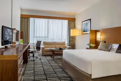 a hotel room with a large bed and a living room at Jumeira Rotana – Dubai in Dubai