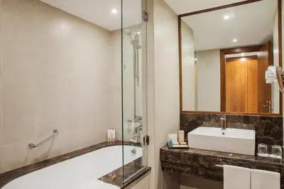 a bathroom with a tub and a sink and a mirror at Jumeira Rotana – Dubai in Dubai