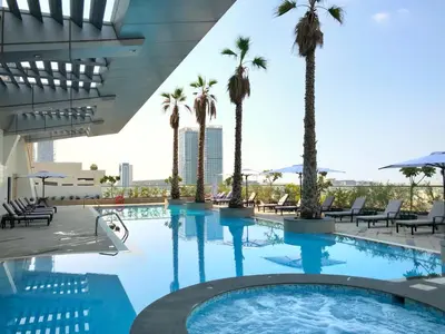 a swimming pool with palm trees and a building at Staybridge Suites Dubai Financial Centre by IHG in Dubai