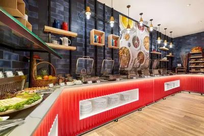 a restaurant with a counter with plates on it at La Quinta by Wyndham Dubai Jumeirah in Dubai