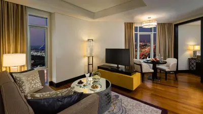 a living room with a couch and a tv and a table at Kempinski Hotel Mall of the Emirates, Dubai in Dubai