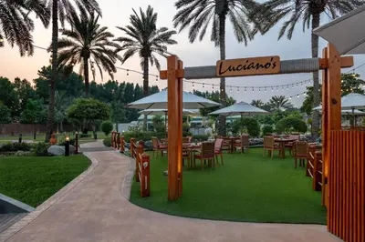 a restaurant with tables and chairs and palm trees at Al Habtoor Grand Resort, Autograph Collection in Dubai