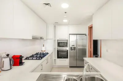 a white kitchen with a stove and a refrigerator at Spacious 3BR in Downtown, Direct Access to Dubai Mall & Metro, Burj Khalifa Views in Dubai