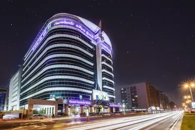 a large building with purple lights on it at night at Grand Excelsior Hotel Bur Dubai in Dubai