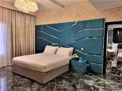 a bedroom with a large bed with a blue headboard at Majestic City Retreat Hotel in Dubai