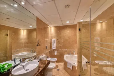 a bathroom with two sinks and a shower and a tub at Majestic City Retreat Hotel in Dubai
