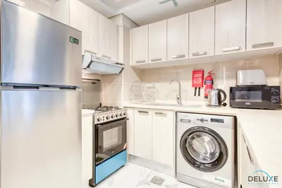 a kitchen with a refrigerator and a washing machine at Distance Away From Expo City Dubai 1BR Unit, MAG 510, Madinat Al Mataar by Deluxe Holiday Homes in Dubai