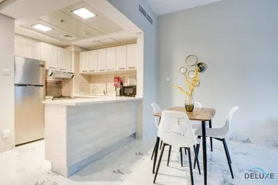a kitchen with a table and chairs and a refrigerator at Distance Away From Expo City Dubai 1BR Unit, MAG 510, Madinat Al Mataar by Deluxe Holiday Homes in Dubai