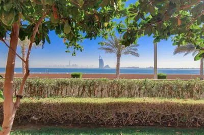 a hedge with trees and the ocean in the background at Luxe Getaways Royal Amwaj Palm Jumeirah Resort Apartment Holiday Home in Dubai