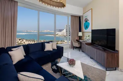 a living room with a blue couch and a large window at Avani Plus Palm View Dubai Hotel & Suites in Dubai