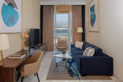 a living room with a blue couch and a desk at Avani Plus Palm View Dubai Hotel & Suites in Dubai