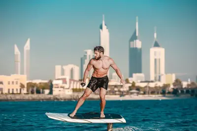 a man standing on a surfboard in the water at Dubai Marine Beach Resort & Spa in Dubai