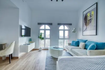 a white living room with a couch and a tv at The Smart Concierge - Discovery Gardens street 4 in Dubai