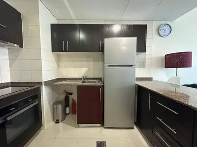 a kitchen with a white refrigerator and a clock on the wall at Awesome Marina Canal View 1BD Bay Central Marina in Dubai
