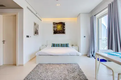 a white bedroom with a bed and a window at Stylish Studio in West Avenue Dubai Marina in Dubai